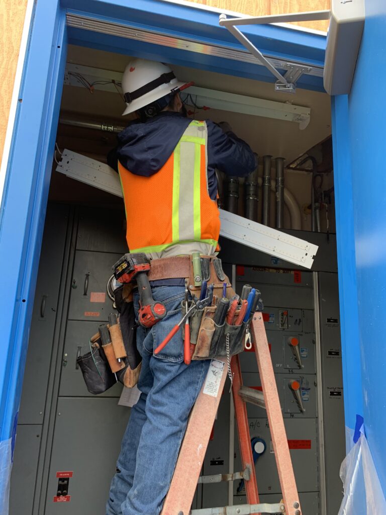 Neal Electric worker on top a a ladder with his equipment